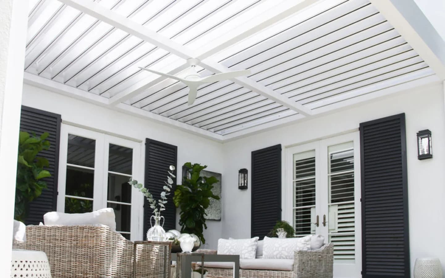 Clean white aluminum louvered pergola covering a furnished patio with open roof blades