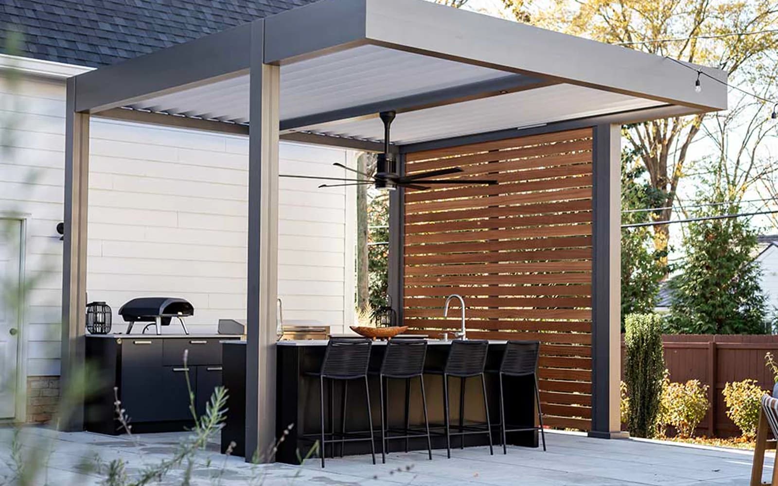 Azenco R-BLADE louvered pergola with a perimeter frame over a backyard outdoor kitchen