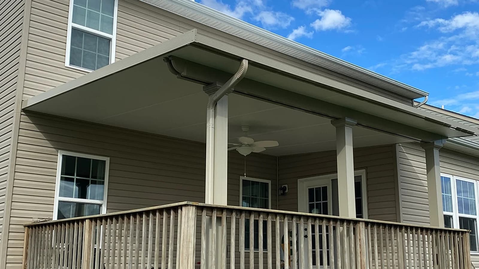 Attached solid-roof patio cover supported above a raised wood deck at a two-story home