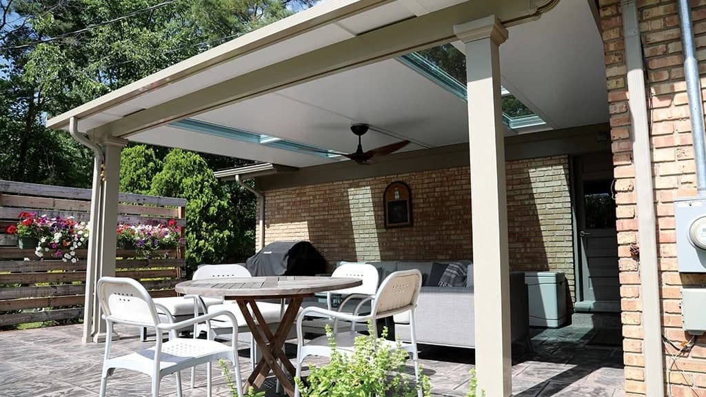Attached insulated patio cover with narrow glazed roof panels above an outdoor dining area