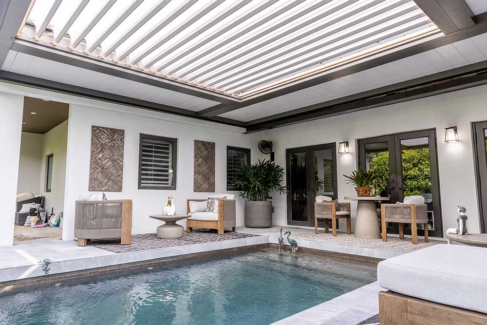 Gray bronze pergola with LED strips illuminating poolside lounge chairs