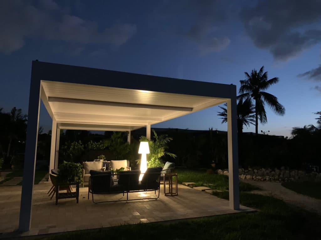 Louvered and fixed roof pergola at evening with ambient lighting