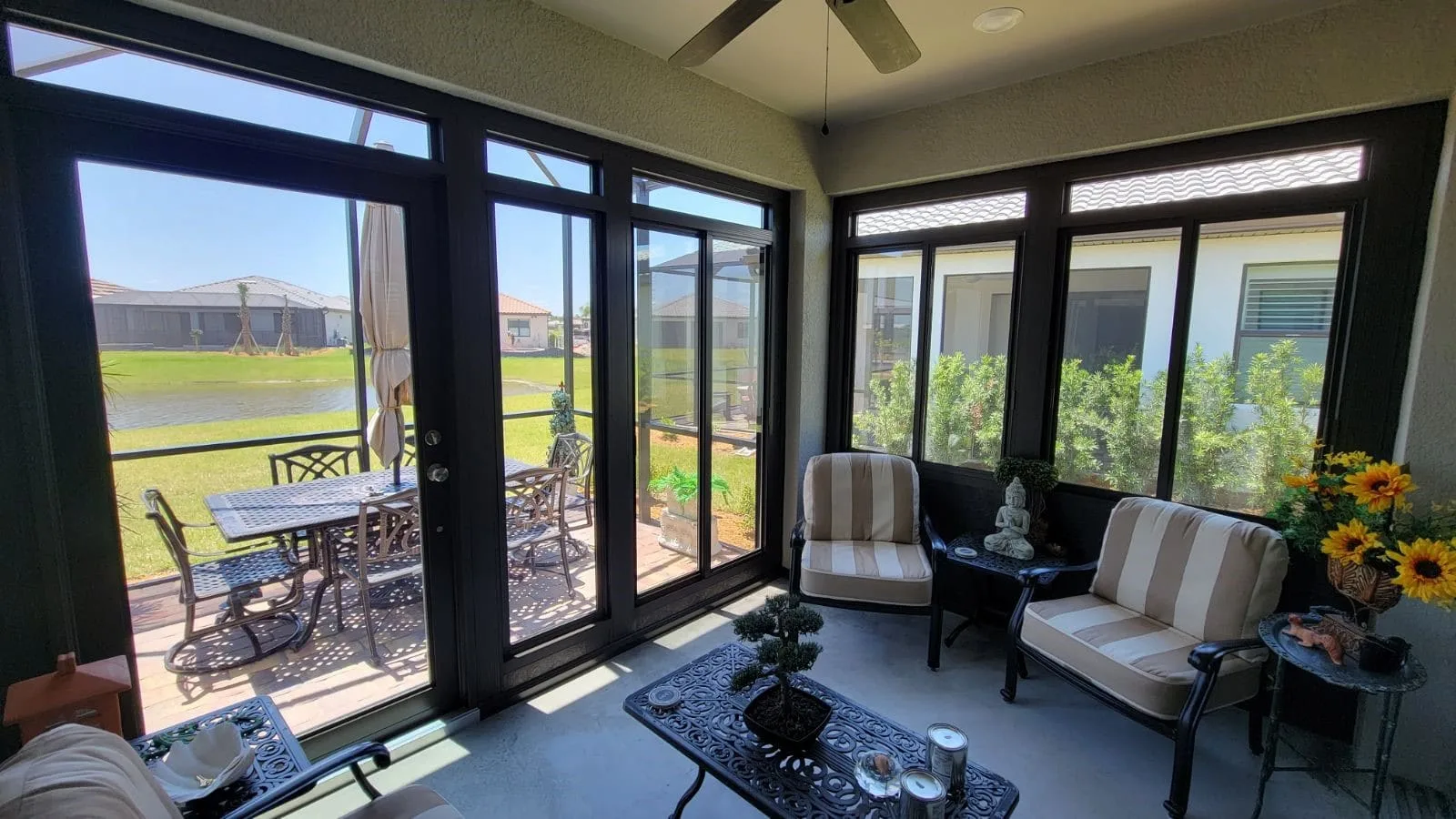 Sunroom interior with dark-framed glass doors, transom windows, and windows overlooking a lawn